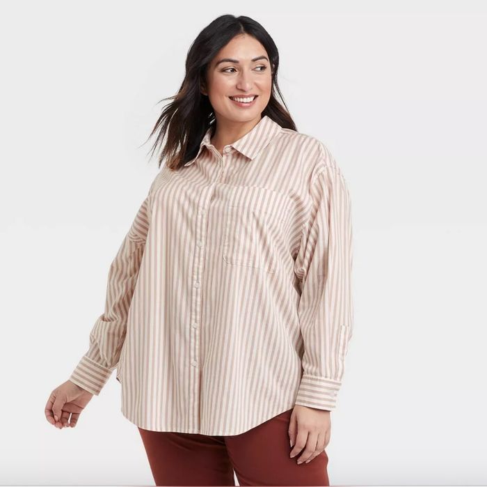 The model is rocking a beige and white pinstriped oversized boyfriend shirt paired with red pants.