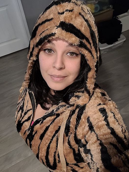 A reviewer rocking a black and tan tiger-print hoodie with the hood up for extra coziness.