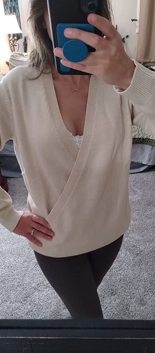 A reviewer wearing a beige V-neck sweater
