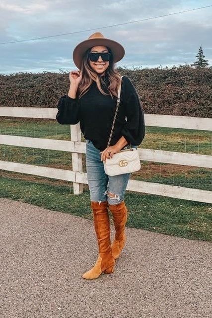 A reviewer is seen wearing the sweater in a classic black hue.