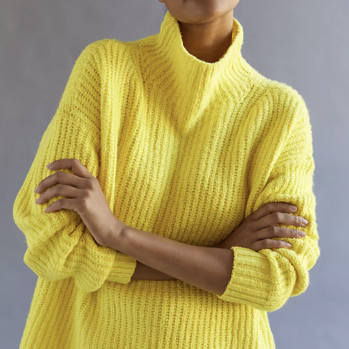 Model posing in a yellow funnel-neck sweater
