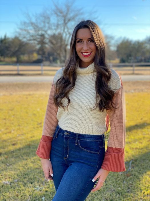 A reviewer wearing a white and pink colorblock turtleneck sweater