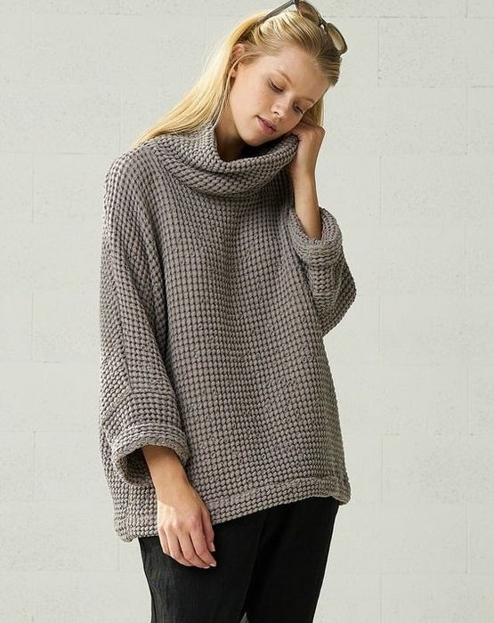 The model is styled in a chunky gray linen sweater, matched with loose black pants.