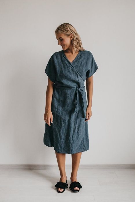 A model wearing a below-the-knee, oversized dark blue wrap dress