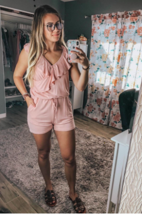 A reviewer wearing the pale pink sleeveless romper with a tie-waist design
