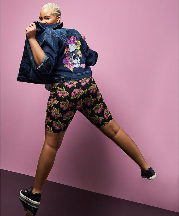 The model is wearing black shorts with a pink cherry design.