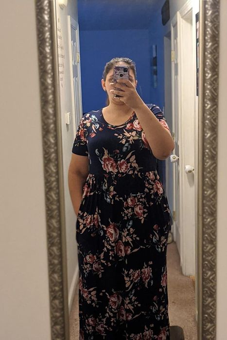 A reviewer wearing the black and pink floral dress with one hand in a pocket