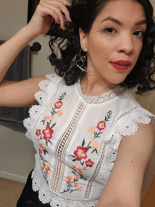 a close-up of the white top with red floral embroidery on a reviewer