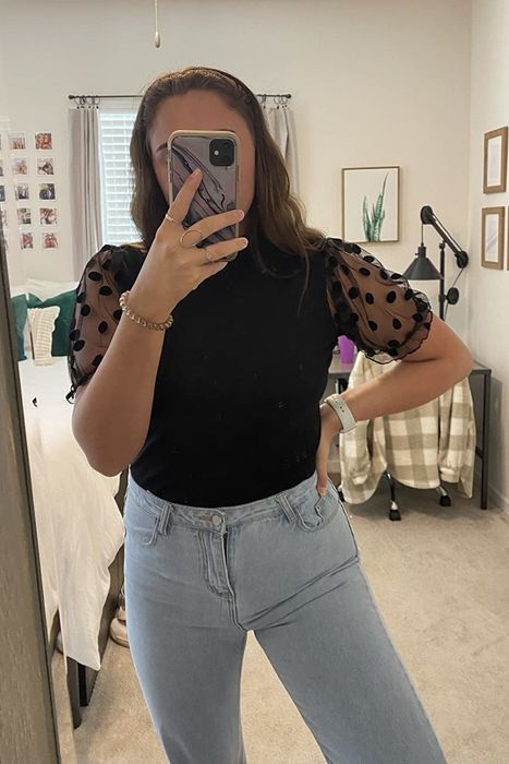 a reviewer posing in the mirror while wearing the black top
