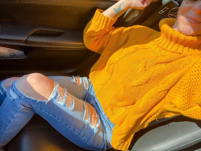 The reviewer pairs a vibrant yellow turtleneck sweater with trendy distressed blue jeans.