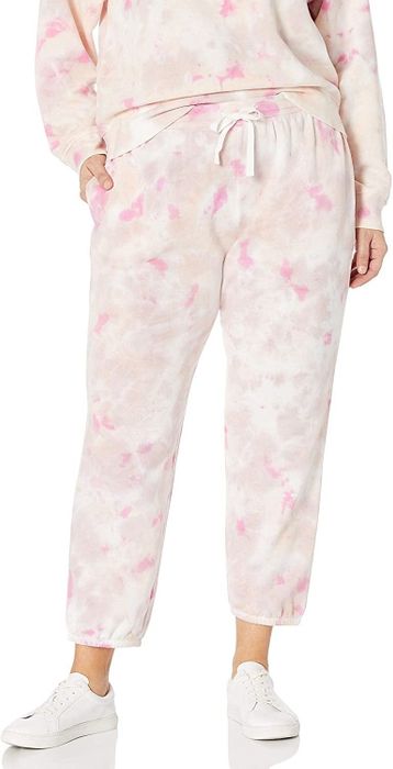 A model wearing the pink sweatpants featuring a drawstring waist, with one hand in a pocket