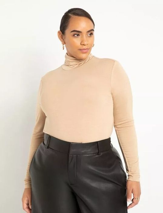 Model wearing a beige turtleneck paired with a black skirt