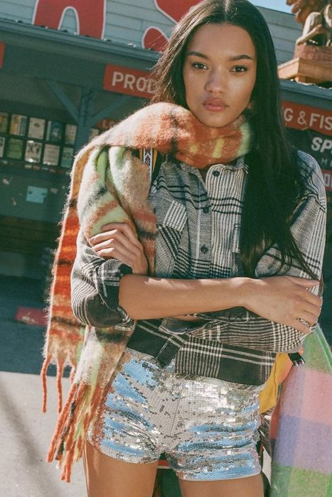 A model is styled in a black and white cropped flannel, paired with a scarf.