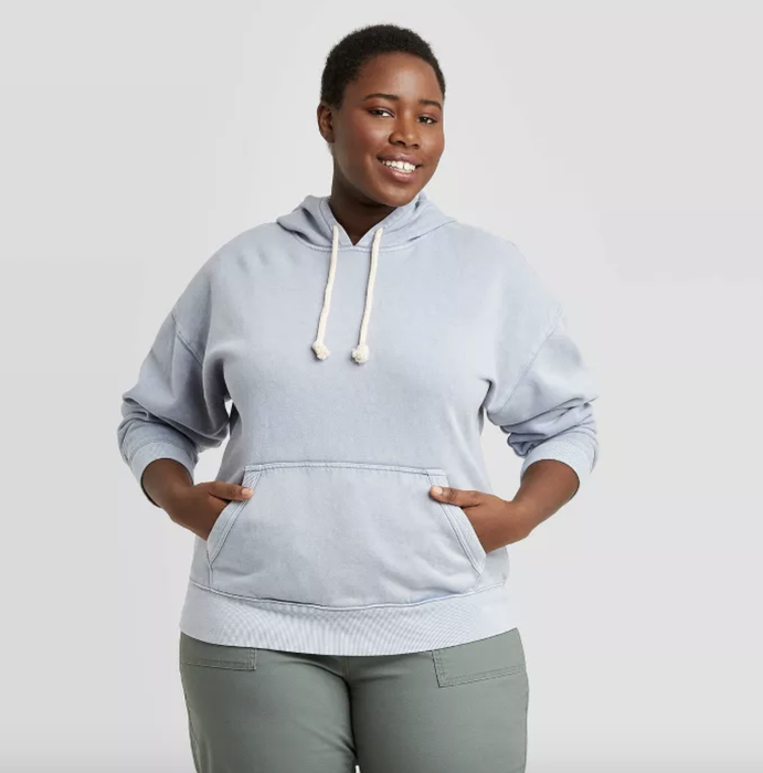 The model is wearing a blue hoodie with white drawstrings.