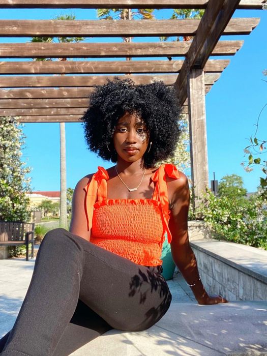 a reviewer seated while wearing the orange top