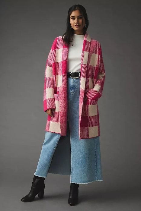 The model is wearing a pink and white plaid cardigan over a white top and jeans.