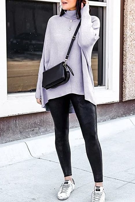 The model is wearing a lavender asymmetrical sweater layered over black leggings.