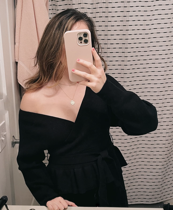 A customer review photo showcasing the black sweater worn off-shoulder