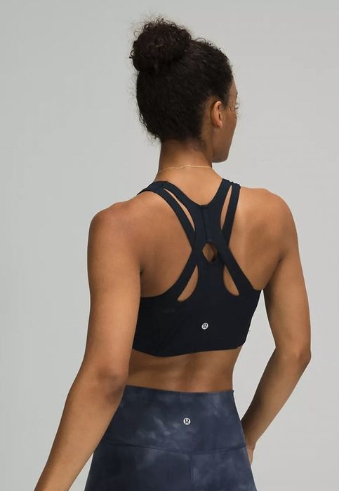 View of the model from the back, showcasing the black sports bra with its unique criss-cross design across the back.