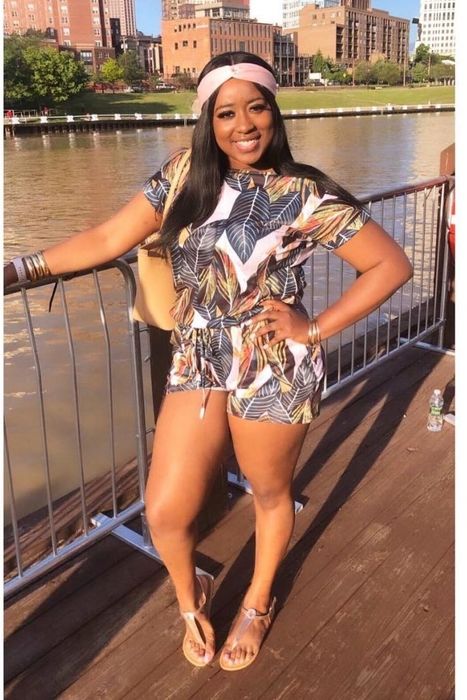 A reviewer showcasing the white and green leaf-print romper with a tie-waist design