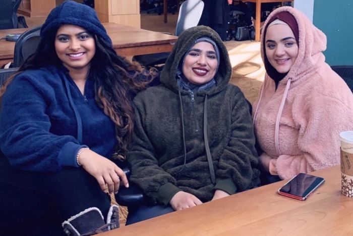 A group of friends, each sporting blue, green, and pink fleece pullovers.