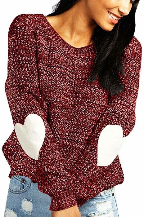 The model is wearing a burgundy sweater adorned with white heart designs on the elbows.