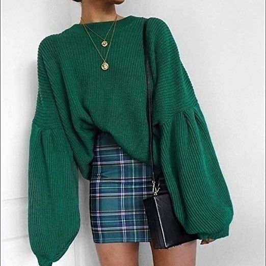 The model showcases an emerald green sweater with striking oversized lantern sleeves.