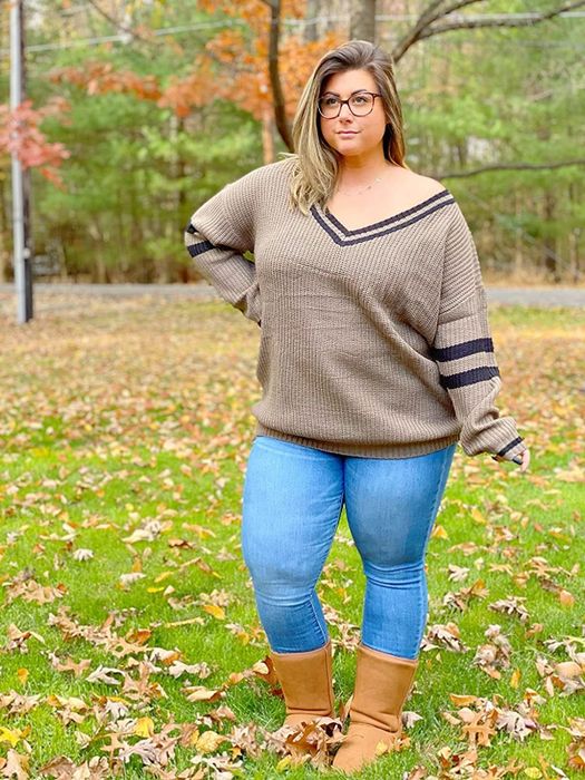 A reviewer posing outdoors in a khaki sweater paired with blue jeans and brown boots