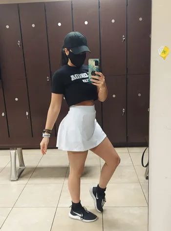 Reviewer displaying the front of the mid-thigh-length white tennis skirt