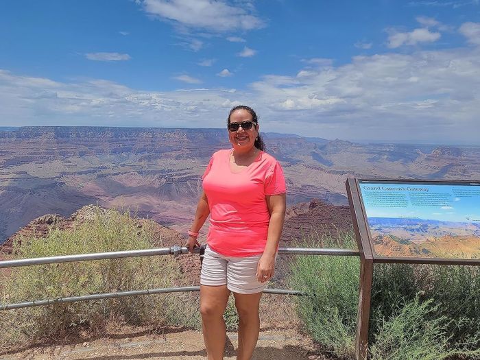 Reviewer in a casual t-shirt and shorts standing near a Grand Canyon information sign