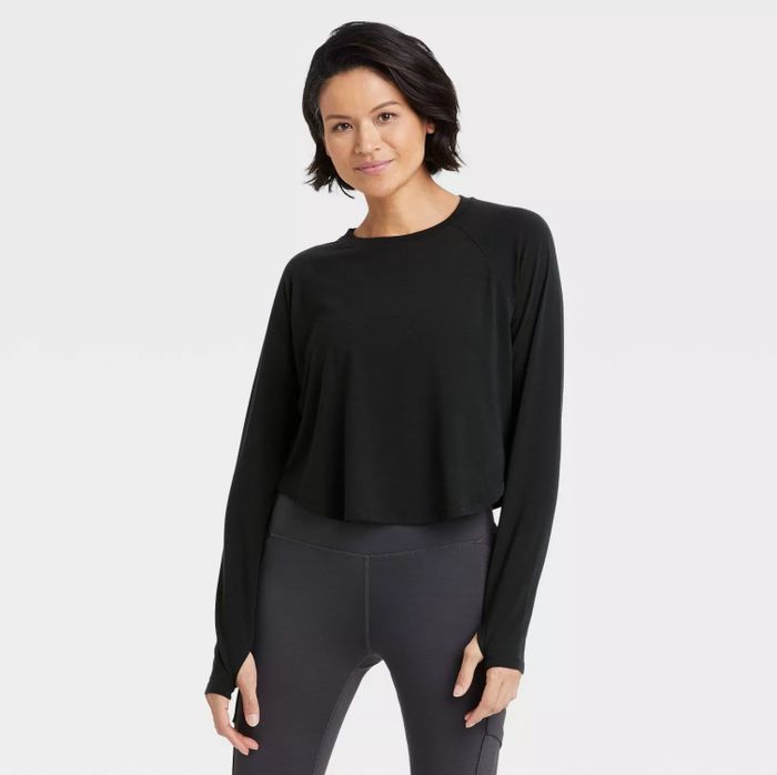 The model showcases the black crop top paired with dark gray leggings.