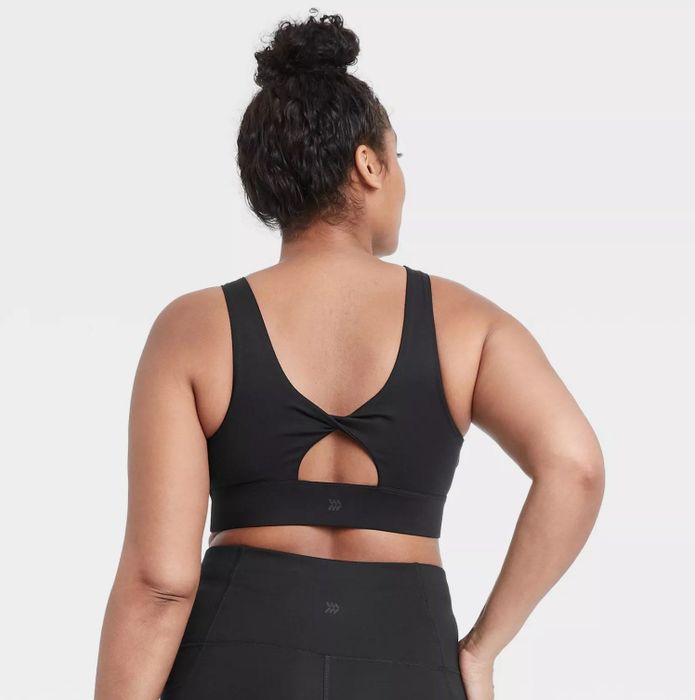The model showcasing the unique twisted back design of the sports bra, complemented by sleek black pants