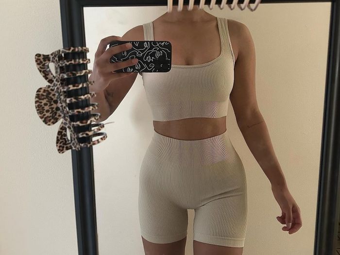 Person wearing a ribbed tank top and shorts set taking a mirror selfie with a phone