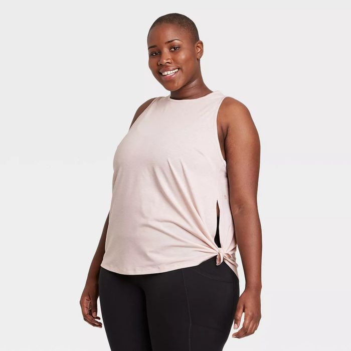 A model wearing the pink top with a side knot detail, paired with sleek black leggings
