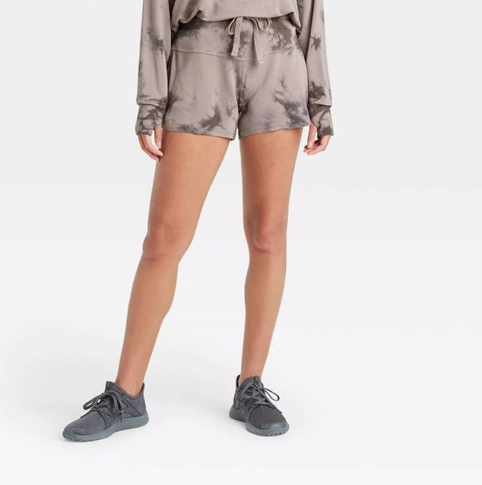 A model styled in gray and brown tie-dye shorts paired with a matching long-sleeve top and gray sneakers