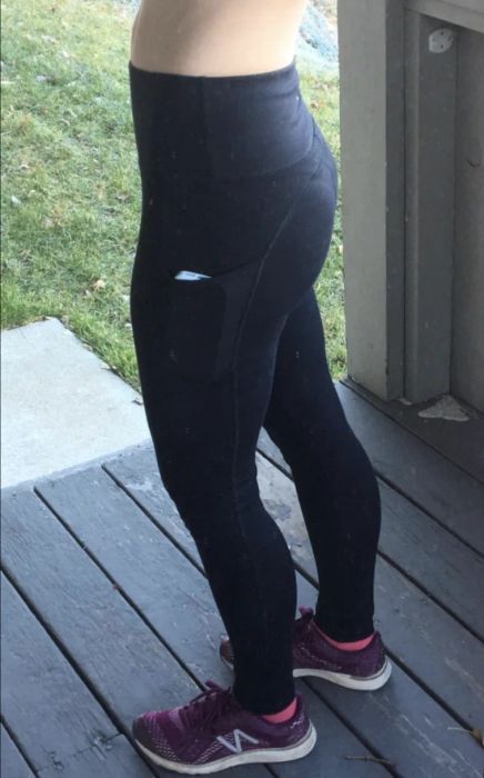 A reviewer in the black version demonstrating the side pocket holding a phone
