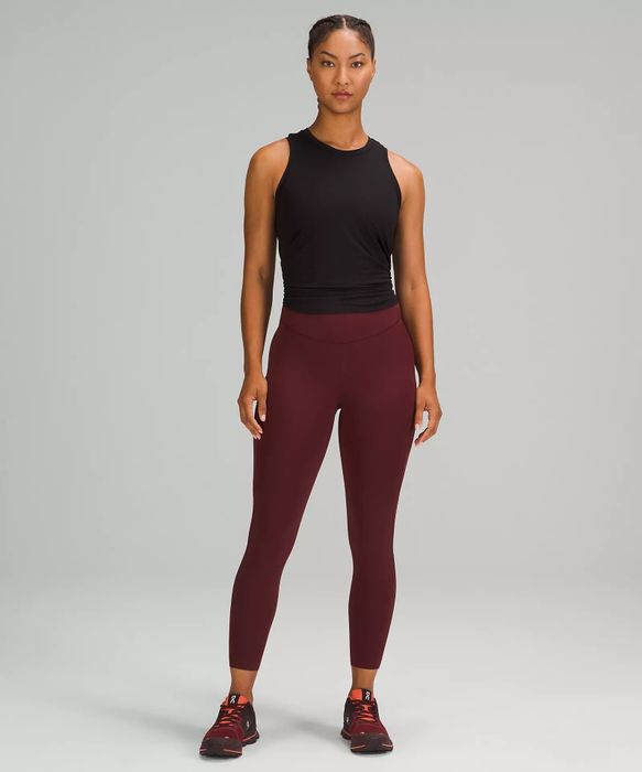 Model showcases dark red cropped high-rise running tights paired with a black workout tank top