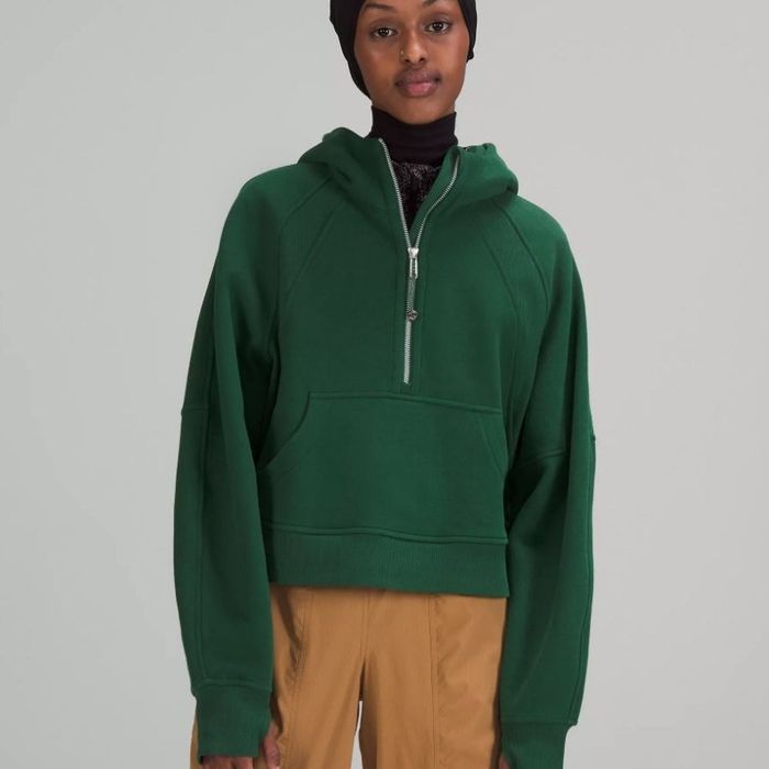 A model wearing an oversized half-zip hoodie in green.