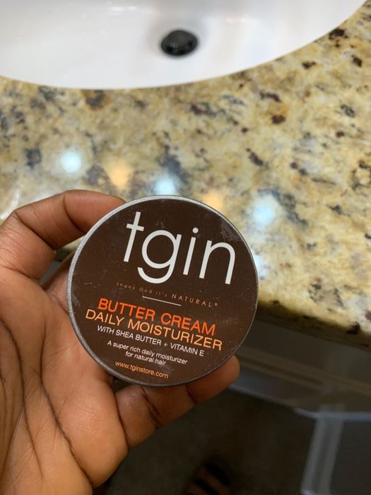 Reviewer holding a jar of TGIN Butter Cream