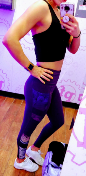 The reviewer is sporting the same style of leggings, matched with a black crop top and crisp white sneakers.