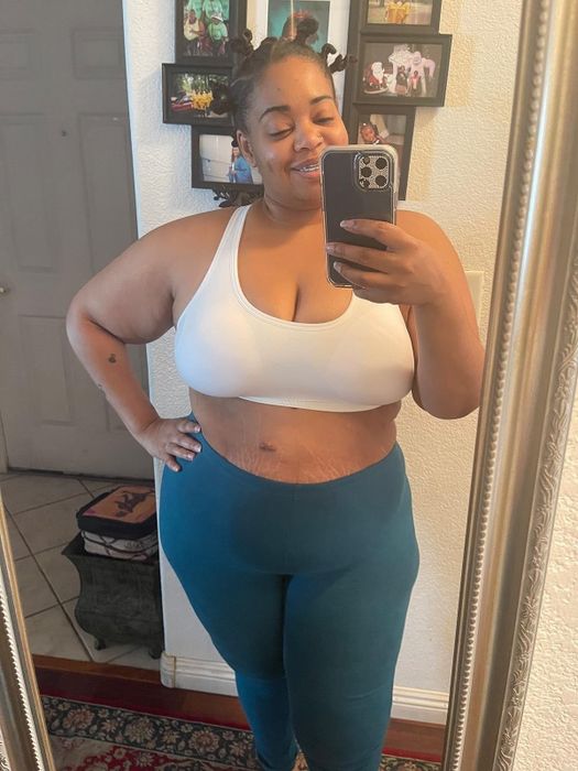 Reviewer smiling in a mirror selfie, wearing a sports bra and leggings