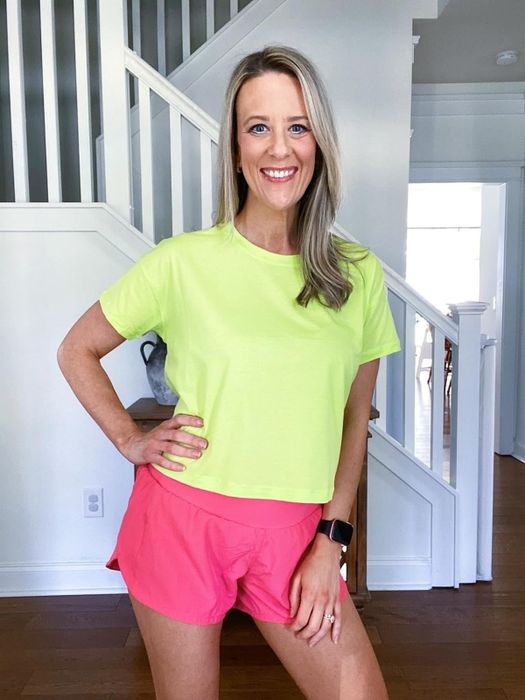 Reviewer in vibrant workout gear posing with a hand on their hip, smiling, in an indoor setting