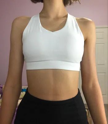 A reviewer wearing a white scoop neck sports bra