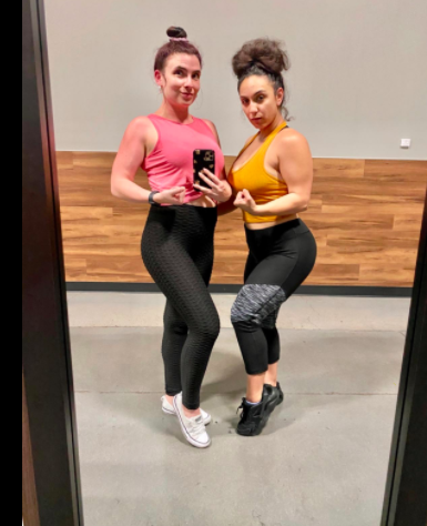 Reviewer models a pink twist-front crop top paired with black leggings at the gym
