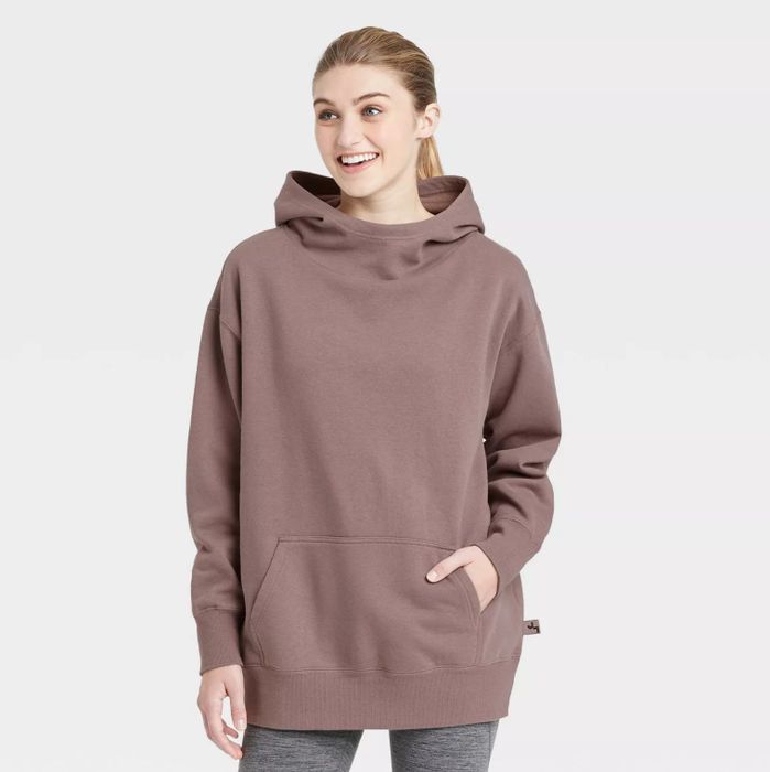 A model wearing the rose-colored hoodie paired with gray leggings