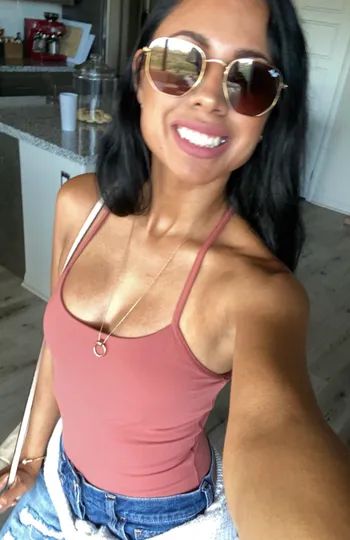 A reviewer modeling the pink strapped tank top from the front