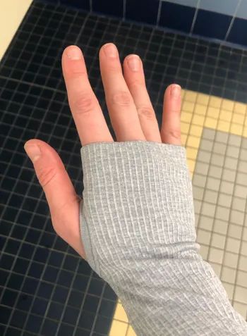 Reviewer demonstrating the sleeve of the gray version with their thumb tucked into the thumbhole