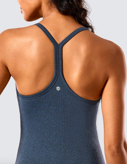 The model is wearing a dark blue seamless racerback tank top, showcasing its sleek and functional design.