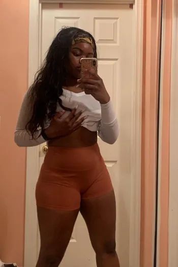 A reviewer modeling orange high-rise bike shorts