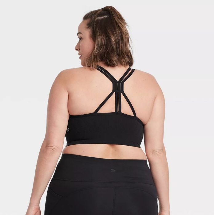 The model showcasing the bra’s intricate back strap design, styled with matching black bottoms